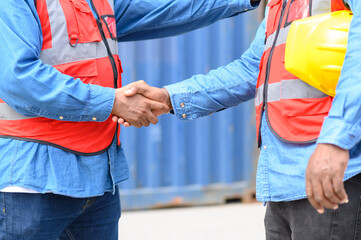 Close up to African African american engineer handshake together at container cargo yard in successful. success in logistics business import export industry.