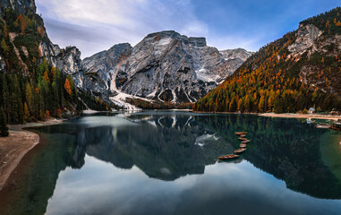 Lake Braies, Italy - Aerial panoramic view of Lake Braies (Lago di Braies) in the Italian Dolomites at South Tyrol with blue sky, wooden boats and reflecting Seekofel Mountain at autumn morning