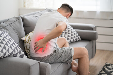 Back pain, kidney inflammation, man suffering from backache at home - 612404425