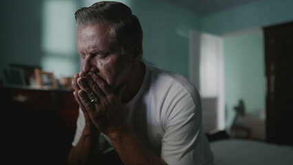 Desperate senior man covering face suffering from despair and lonliness. Older middle-aged person...