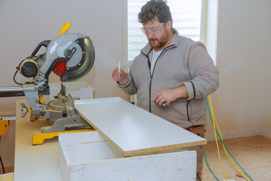 Worker cutting melamine board with circular saw for shelves
