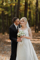the bride and groom against the background of a fairy-tale fog in the forest, he kisses her on the...