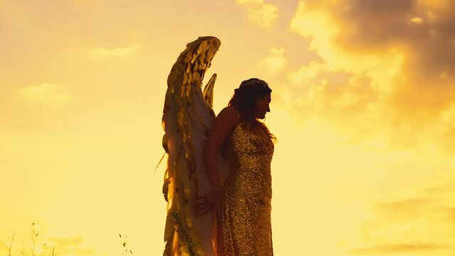 Dark shadow silhouette Fantasy woman angel raises hands to sky in prayer beauty golden white wings long dress costume. magic divine sun light sky. Art portrait Fairy girl goddess queen sexy lady. 4k