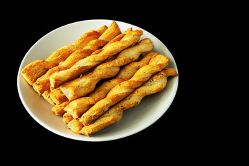 Sticks of buttery yeast dough on a plate on a black background