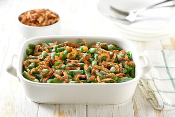 green bean casserole with crispy fried shallots and cream sauce in a ceramic cooking baking dish.