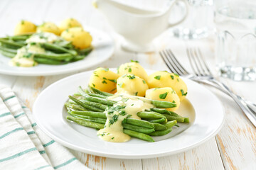 green bean with cream sauce and boiled potatoes on white table, selective focus. Vegetarian,...