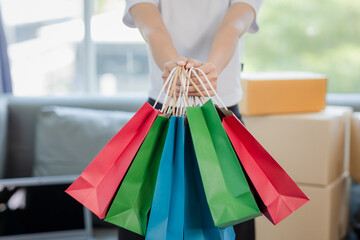 Portrait of beautiful smiling Asian woman in white shirt holding shopping bags posing on white background.