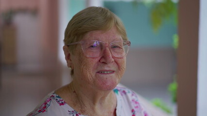 Happy senior elderly lady in her 80s looking at camera in home backyard. Close-up face of an older aged caucasian woman