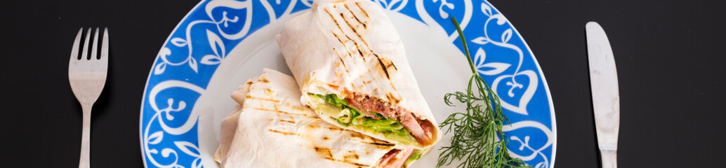 Delicious kebab with meat, lettuce, tomato, onion and sauce with french fries.