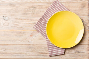 Top view on colored background empty round yellow plate on tablecloth for food. Empty dish on napkin with space for your design