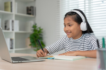 online tutor online course for Asian children. video conference on laptop at home. play back online course, girl student wear earphones to study, notes homework, video classes, new education..