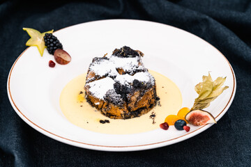 Delicious, colorful dessert decorated with edible flower petals on a white plate against a dark background.