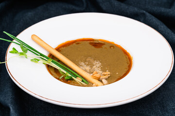 Soup in a white plate on a dark background.
