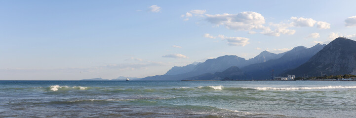 Pebble beach with cloudy blue sky on foggy mountains background