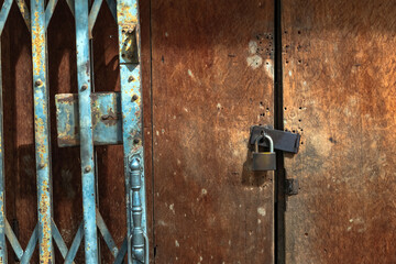 Old gold steel lock and damaged and rusted steel door on wooden door. Locked on wooden door with...