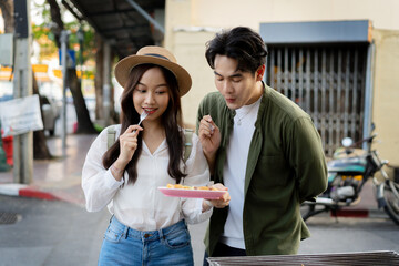  Asian couple traveler wearing a casual wear and hat in relationship buying a dessert snack on...