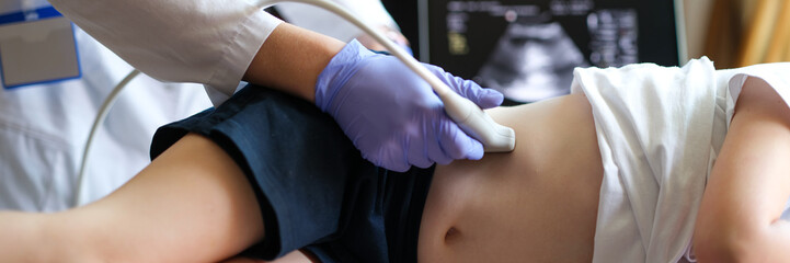 Doctor making examining with ultrasound of internal organs of child in clinic office
