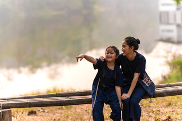 Asian mother and daughter wearing indigo tradtional northern Thai clothes sitting in water park 