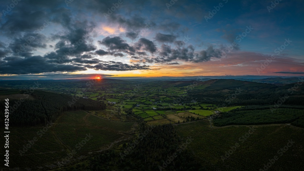 Poster aerial view of greenery fields with dense trees during sunset