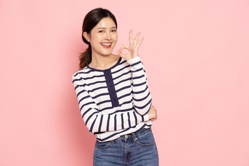 Young Asian woman smiling and showing OK sign isolated on pink background