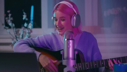 Young woman playing guitar and singing a song, recording video for social media