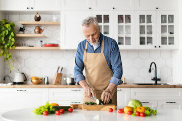 Happy senior man preparing healthy food in kitchen interior