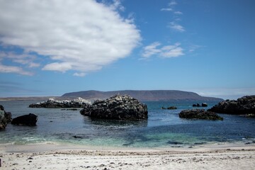 Pieces of rocks in a sea near the coast under the blue sky and clouds