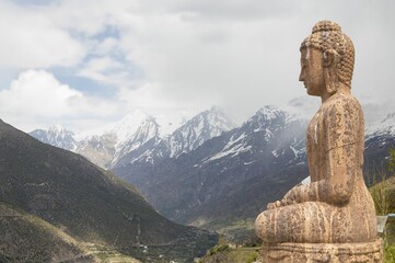 Fototapeta na wymiar Closeup of a Buddha statue on the background of high mountains