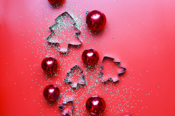Flatly cookie cutters on a red background. Sequins and Christmas toys on a red background