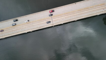 Aerial top view of cars driving along the bridge over the water