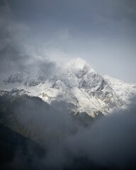 Vertical shot of a breathtaking snowy mountain covered in fog