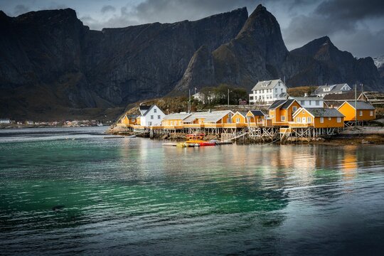 Yellow Buildings At The Shore With Rocky Cliffs In The Background