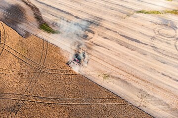 Top view of  a harvester working in a field and mows wheat