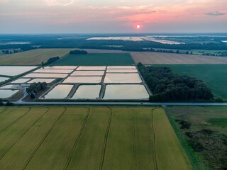 Fototapeta na wymiar Bird's eye view of the fish pond surrounded by a field at sunset