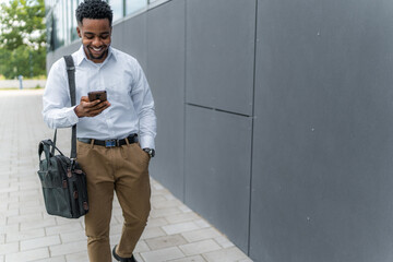 The determined African-American businessman, phone in hand and laptop bag on his shoulder, exudes...