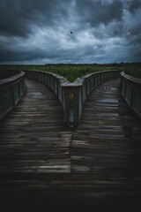 Naklejka na ściany i meble Vertical symmetrical view of a boardwalk slipt into different directions with a cloudy sky
