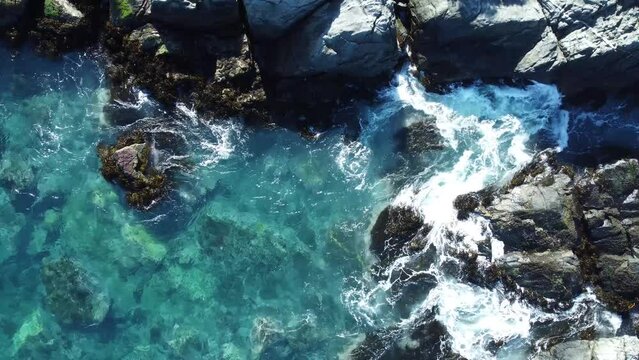 Aerial view of the foamy sea waves splashing over the rocks on Zapallar beach, Chile