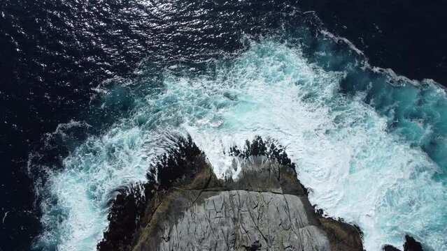 Aerial view of the foamy sea waves splashing over the rocks on Zapallar beach, Chile