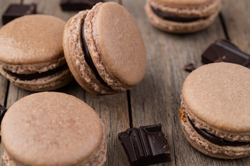 Dark chocolate macarons over wooden background
