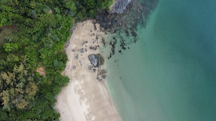 Drone view of Nui Bay beach in Thailand with rocky shore and forests in the background