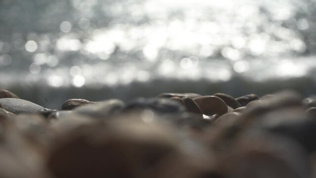 Selective focus of rocky beach and shining sun reflection in the sea
