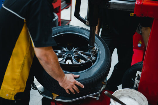 Mechanic changing tires on tire changer in Garage.