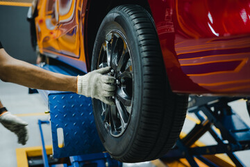 Fototapeta na wymiar Mechanic with repairing car wheel in workshop. Hands using screwdriver to change the tyre of car.