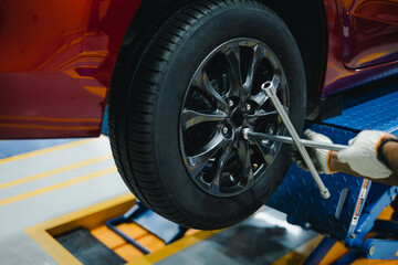 Mechanic with repairing car wheel in workshop. Hands using screwdriver to change the tyre of car.