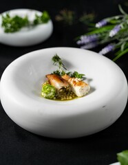 Vertical shot of a stuffed fish with green sauce on a fancy white plate