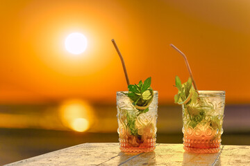 two mojitos against the sunset by the sea