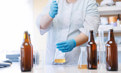 Laboratory assistant inspecting production beer, analysis drink in glasses. Concept brewery food industry