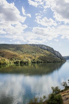 Beautiful landscape of a river between green hills on a sunny day © Rafael Moraes/Wirestock Creators