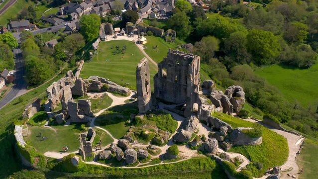 Drone view over the Corfe Castle surrounded by green vegetation in England