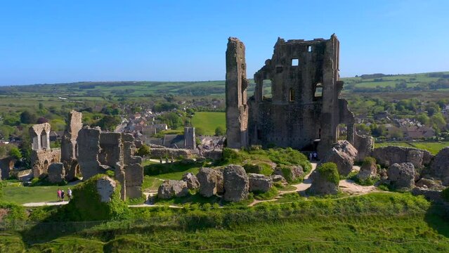 Drone view over the Corfe Castle surrounded by green vegetation in England